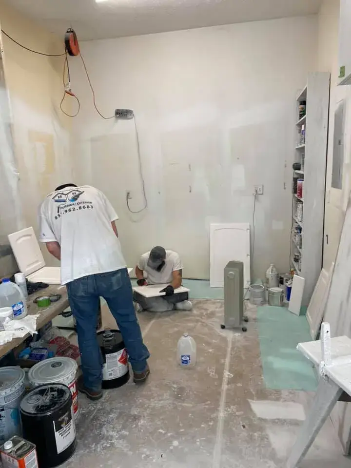In progress: kitchen wood cabinets painted white (patterned tile wall, HOME sign)