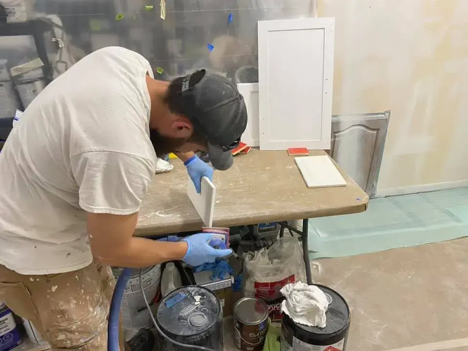 In progress: kitchen wood cabinets painted white (patterned tile wall, HOME sign)