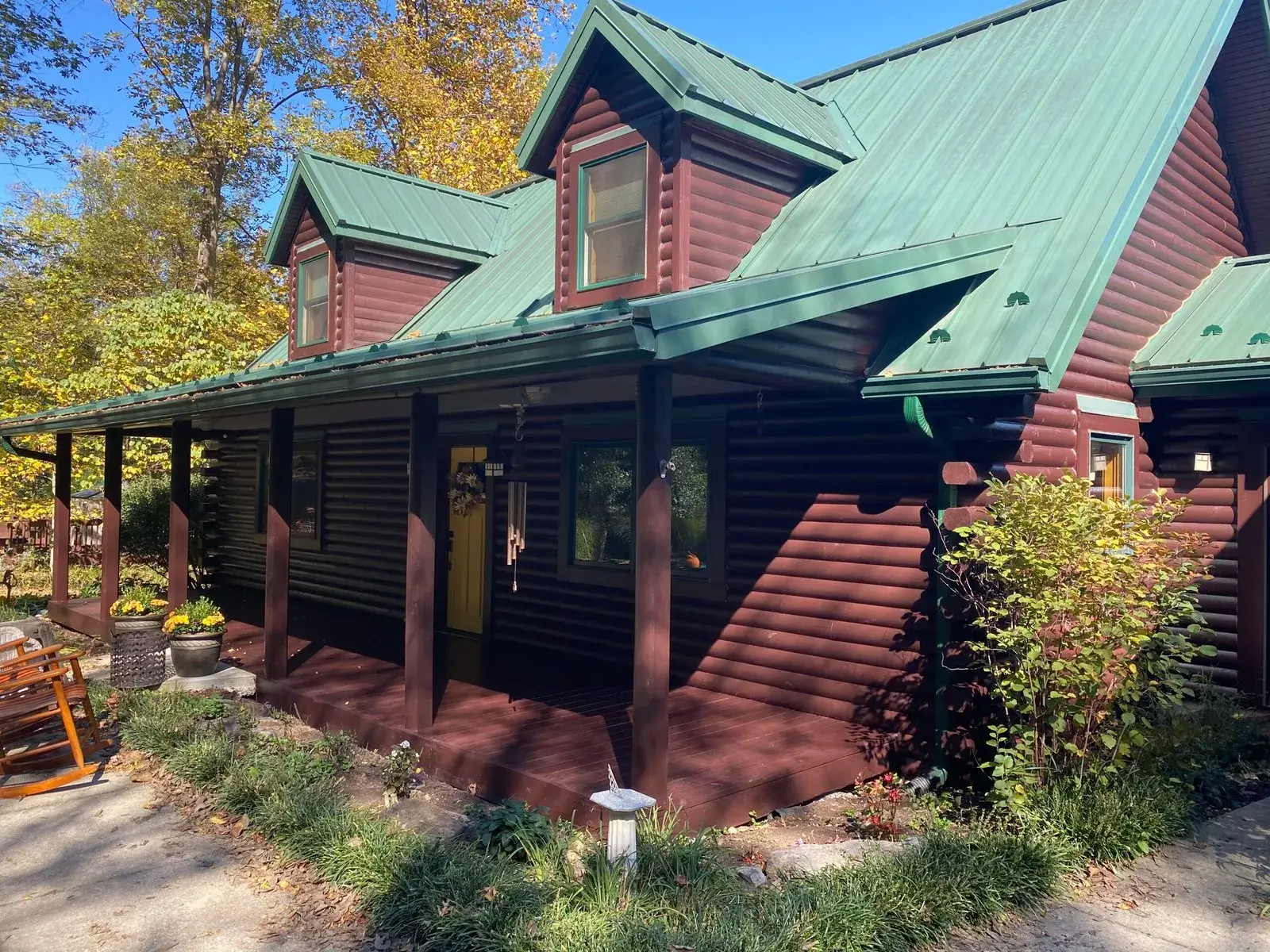 After: log home exterior restained, green metal roof