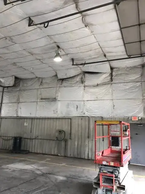Before: metal building interior: walls painted white under insulated fabric ceiling