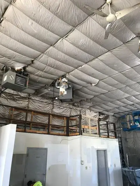Insulated ceiling with a hanging fan and heater above a wooden loft in an industrial space. - My Personal Painter - My Personal Painter In progress: metal building interior: walls painted white under insulated fabric ceiling
