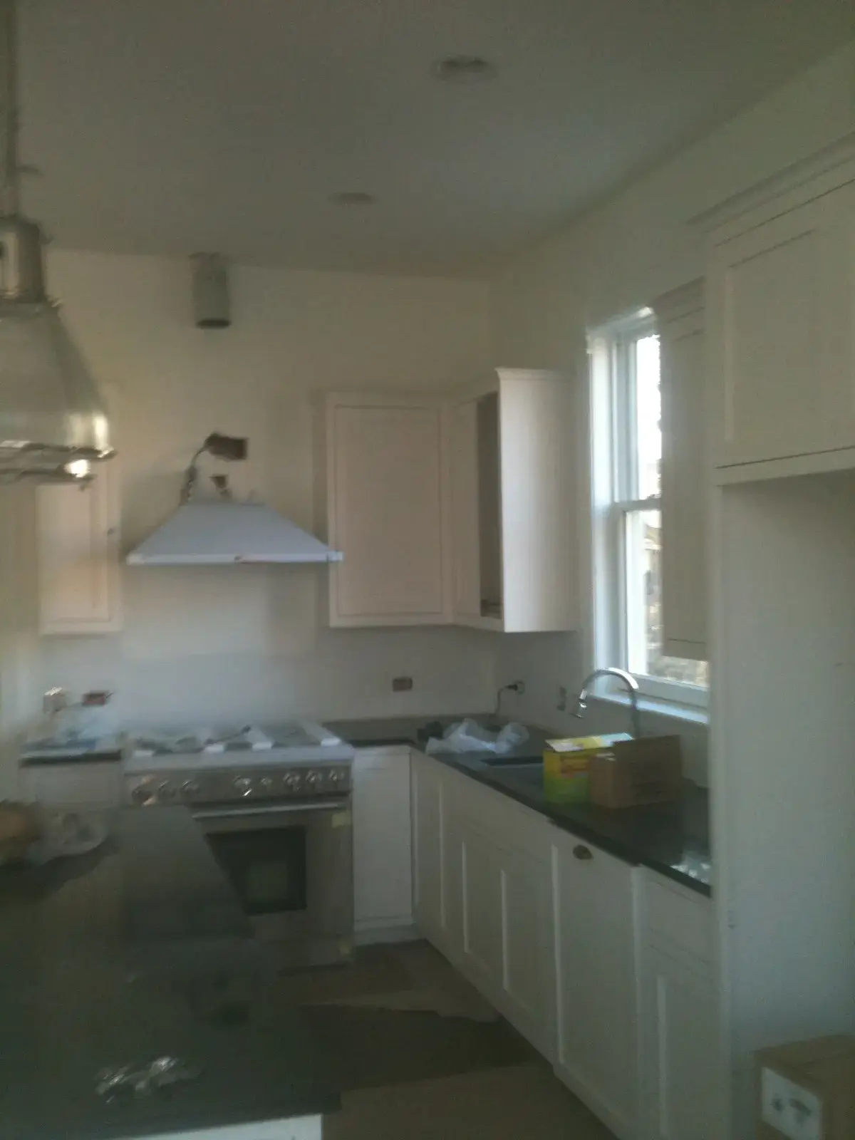 A kitchen under construction with white cabinets, a stainless steel range, and dark countertops. - My Personal Painter - My Personal Painter After: new-build craftsman house: exterior and interior