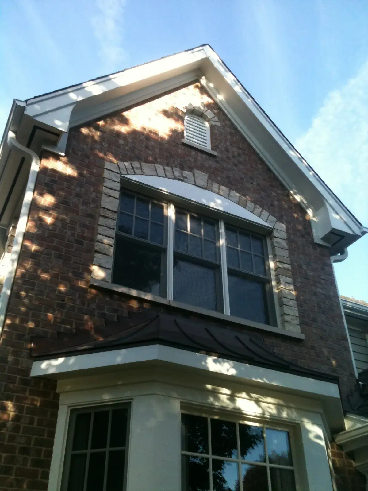 Exterior view of a two-story brick house with a large bay window and a second-story window with a stone arch. - My Personal Painter - My Personal Painter After: new-build craftsman house: exterior and interior