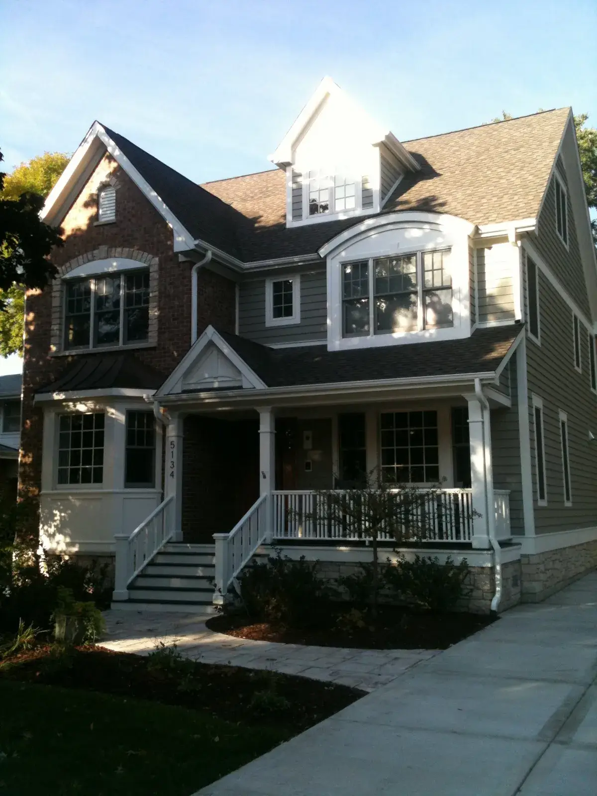 Two-story suburban house with a brick and gray siding exterior, a front porch, and a paved walkway. - My Personal Painter - My Personal Painter After: new-build craftsman house: exterior and interior