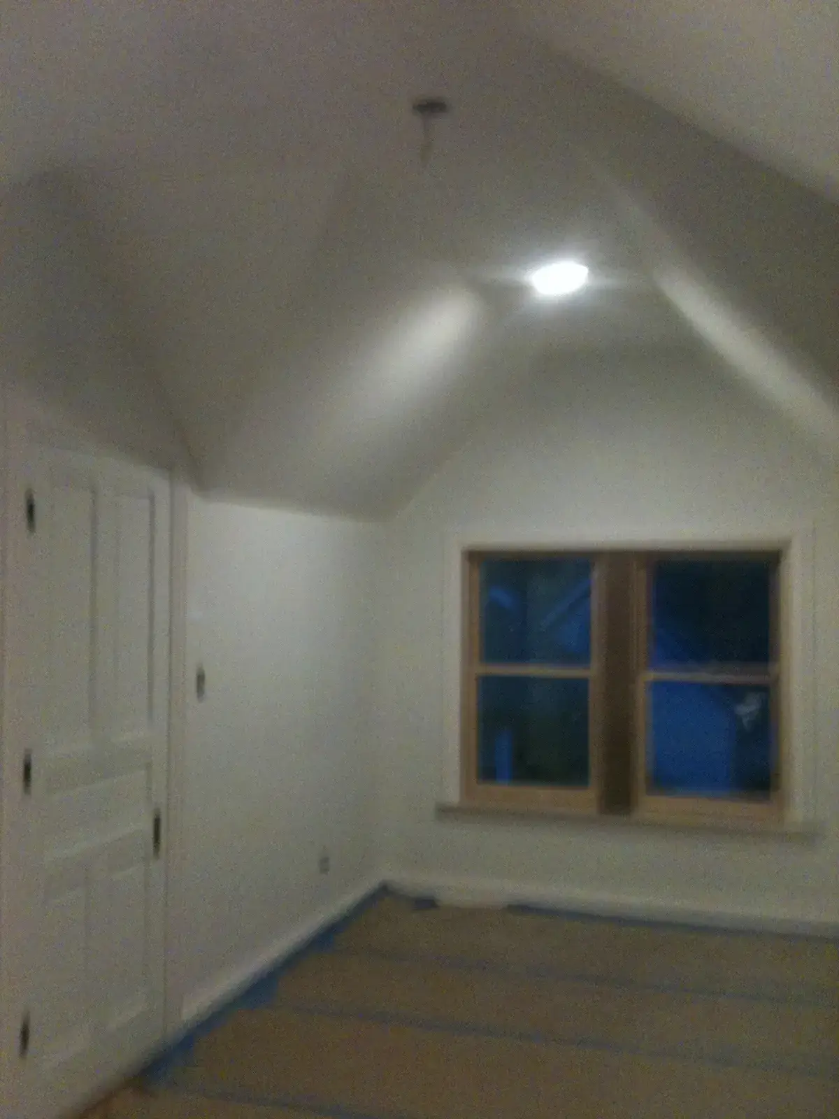 An empty room with white walls, a sloped ceiling, a closed door, and a window. - My Personal Painter - My Personal Painter In progress: new-build craftsman house: exterior and interior