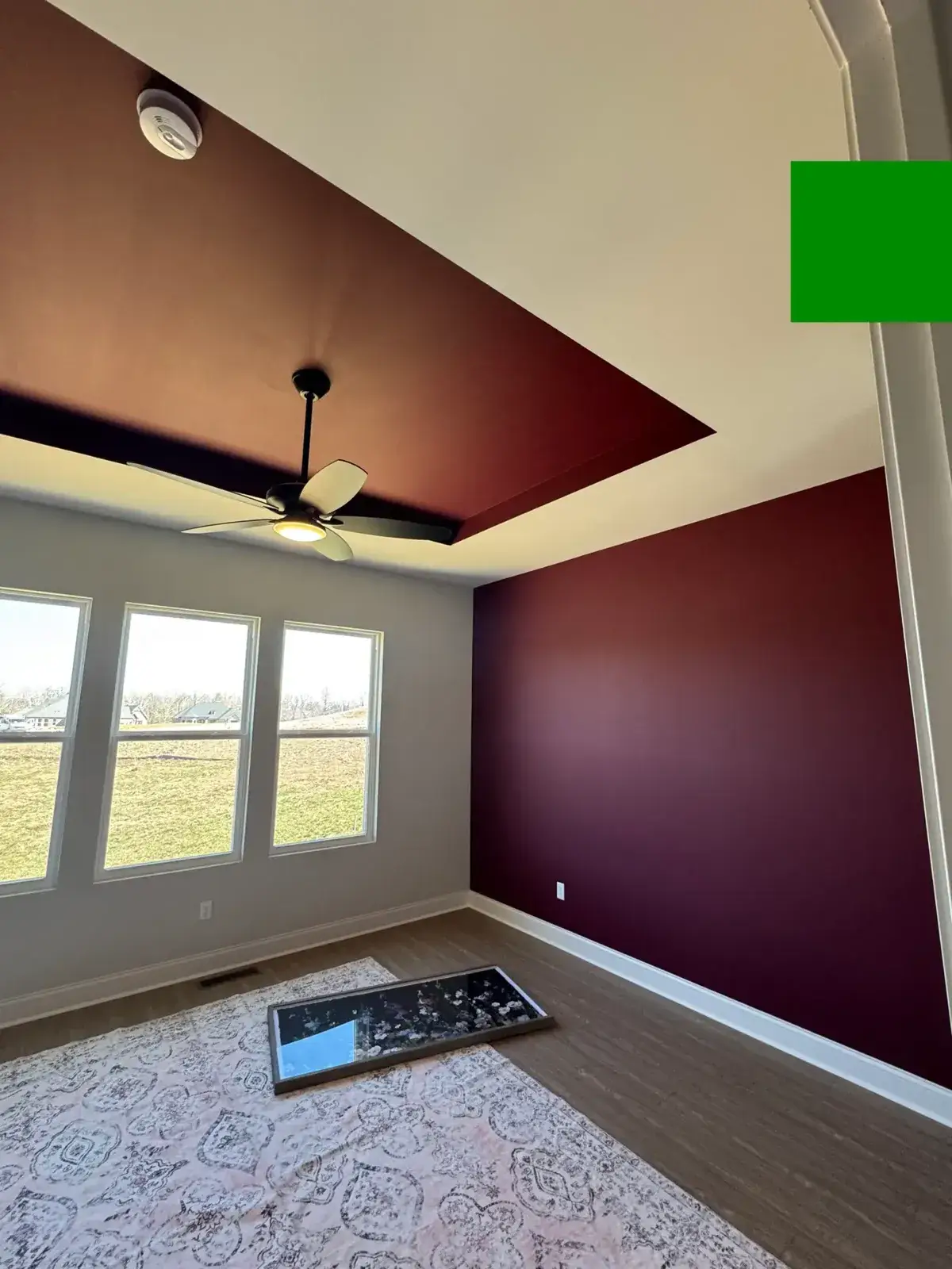 Room with a maroon accent wall and matching ceiling section featuring a lighted ceiling fan. - My Personal Painter - My Personal Painter After: new-build house: black archway, accent walls and doors