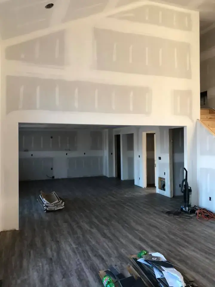 An interior room under construction with newly installed grey flooring and unfinished drywall on the walls. - My Personal Painter - My Personal Painter Before: new-construction home interior painted
