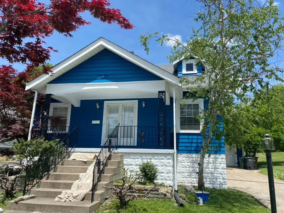 After: red siding house painted blue with white stone foundation