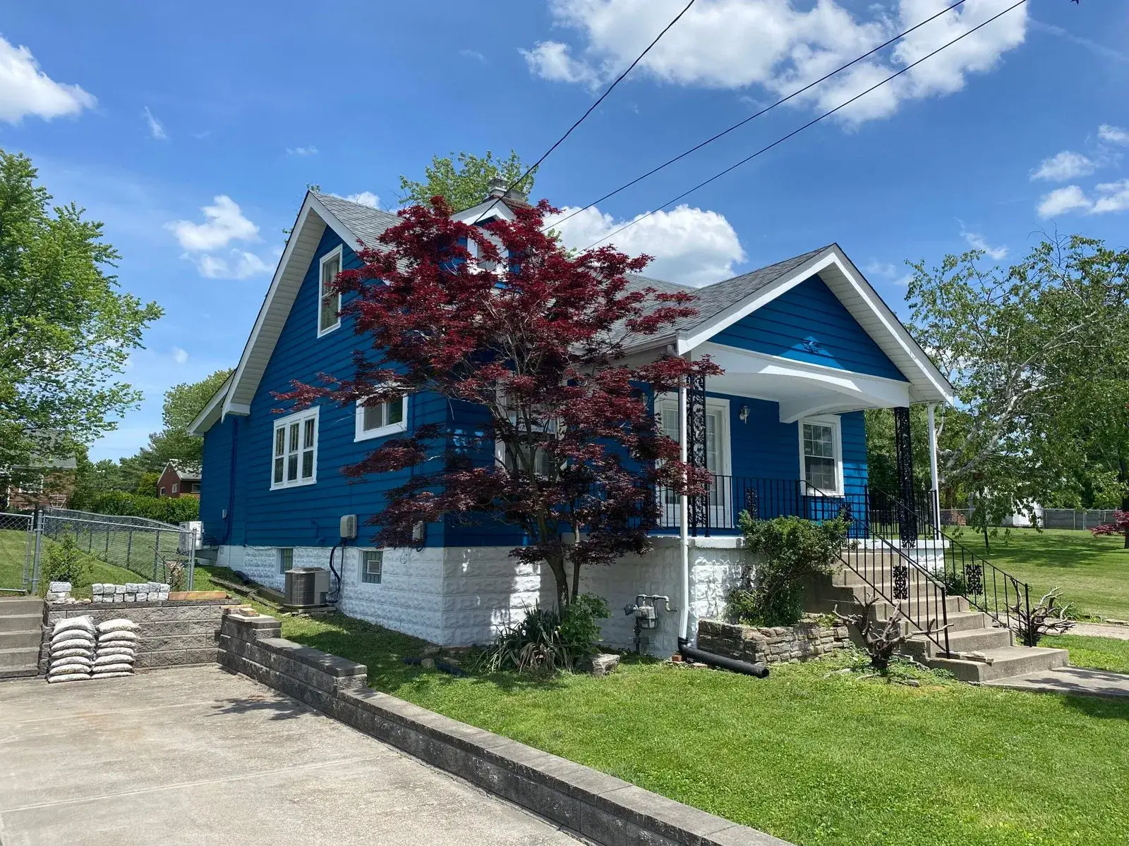 After: red siding house painted blue with white stone foundation