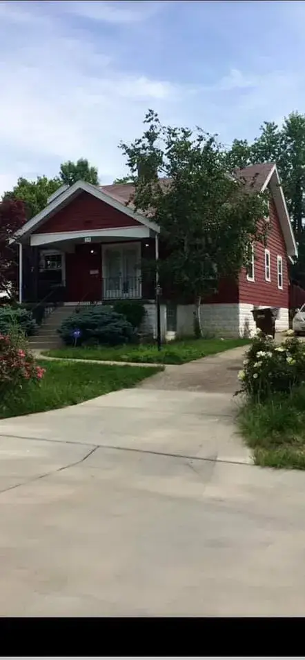 Before: red siding house painted blue with white stone foundation