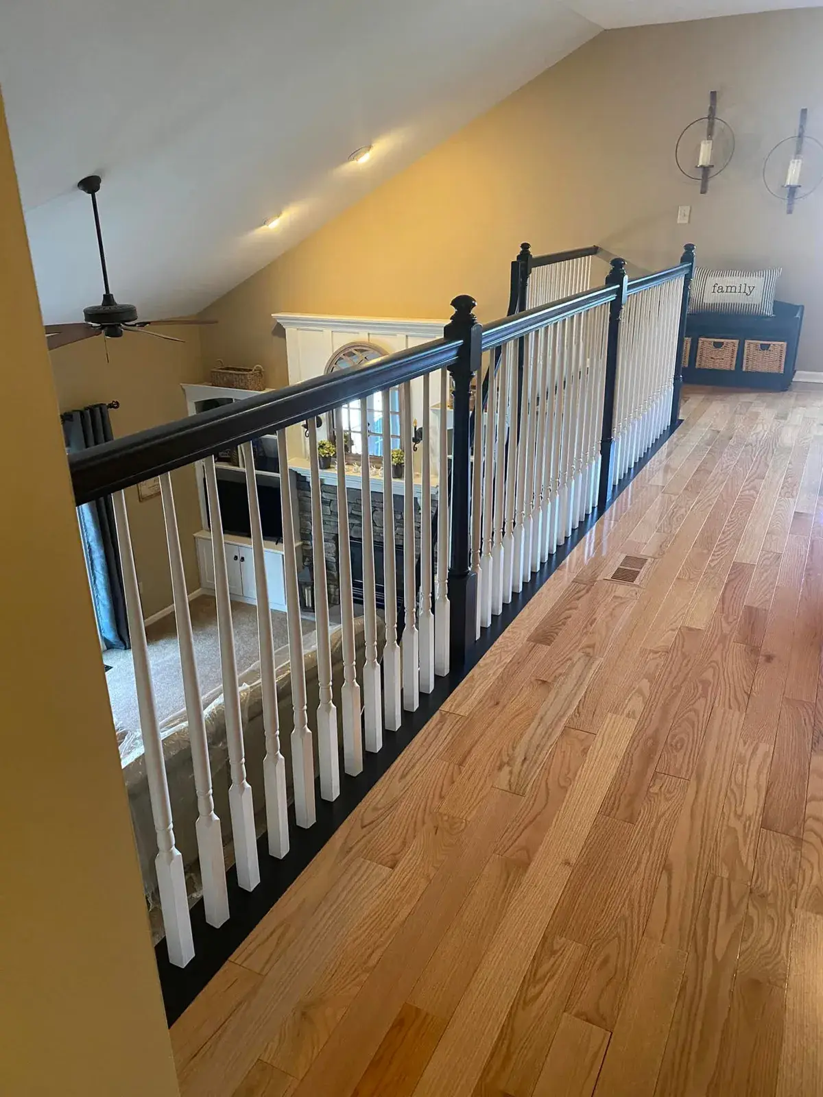 A second-story landing with wood floors and a black and white railing overlooking a living room. - My Personal Painter - My Personal Painter After: staircase: oak railing painted black with white spindles and black treads