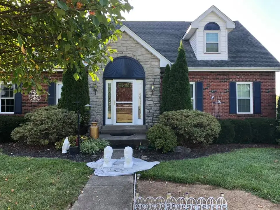 Before: stone and brick Cape Cod: front door, arched sunburst and shutters painted dark blue