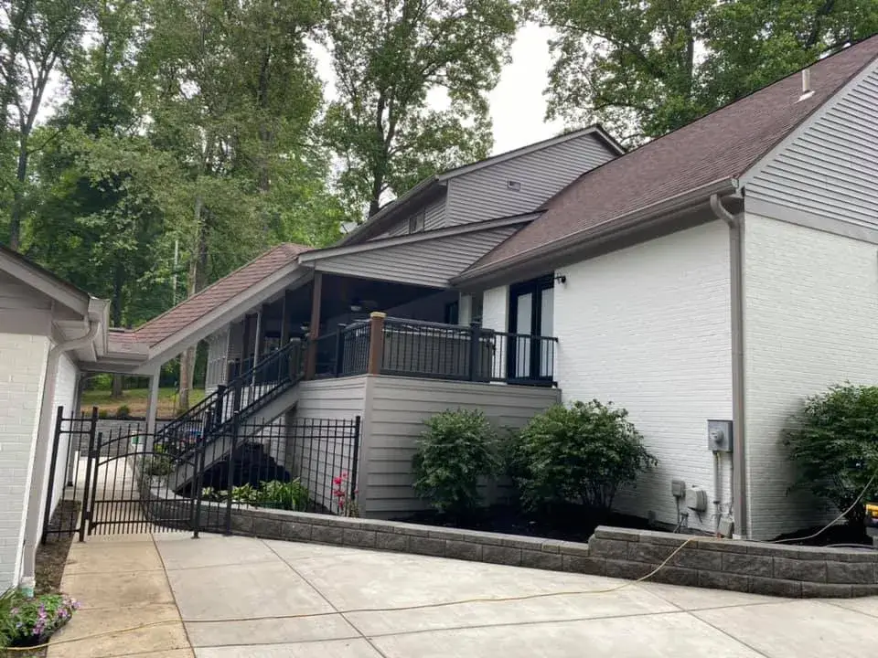 After: two-story brick and siding house painted, red shutters to black