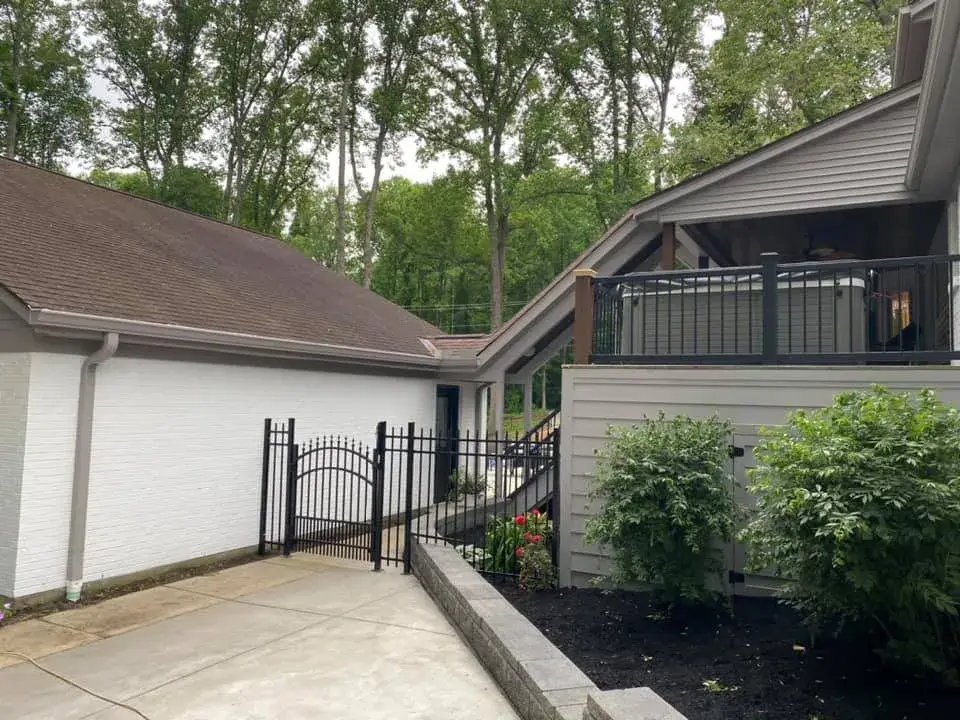 After: two-story brick and siding house painted, red shutters to black