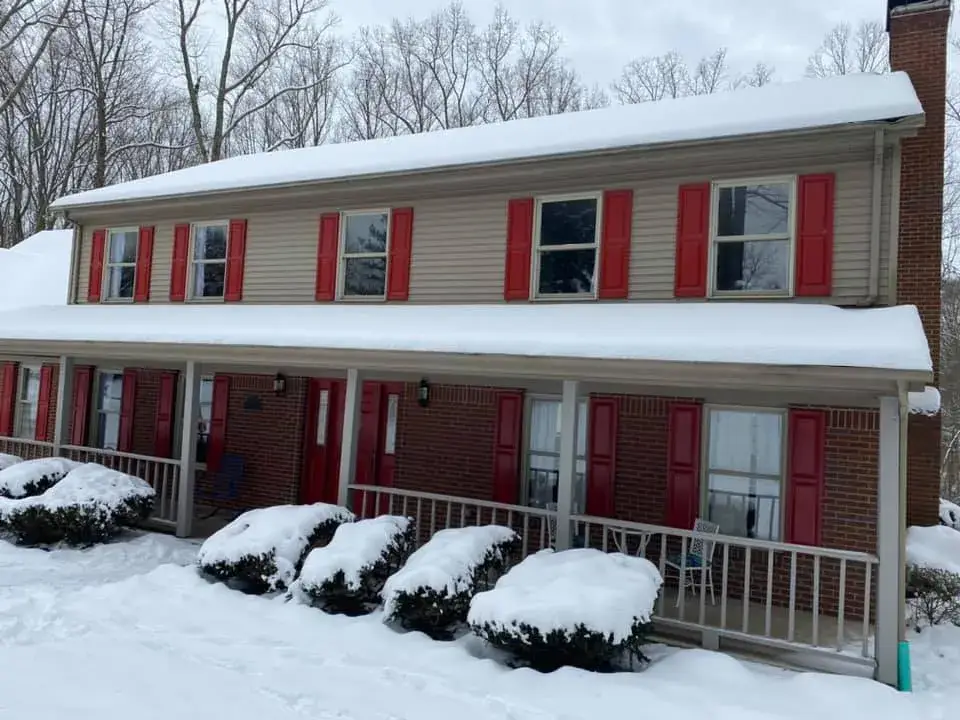 Before: two-story brick and siding house painted, red shutters to black