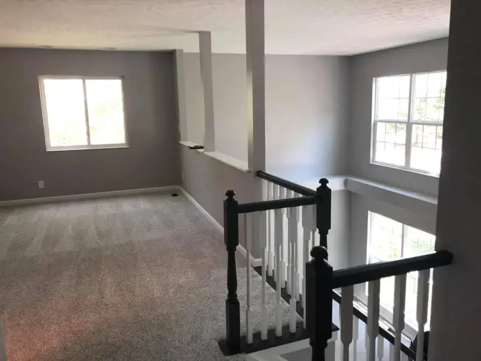 After: two-story foyer and rooms painted gray, stair railing painted black