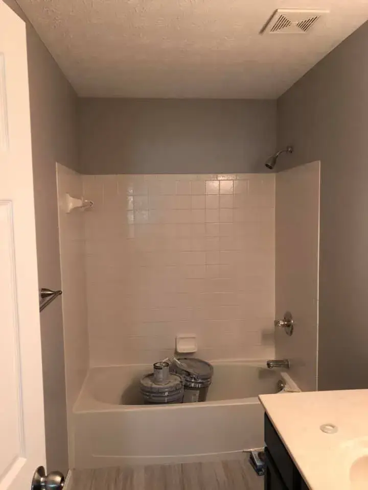 A bathtub with white wall tiles and two paint buckets inside. - My Personal Painter - My Personal Painter After: two-story foyer and rooms painted gray, stair railing painted black