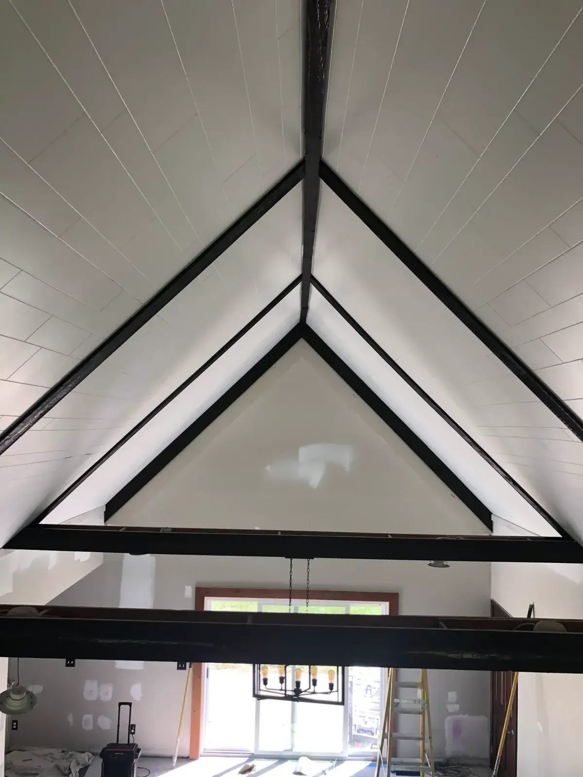 After: vaulted great room: brick chimney painted, then stained wood ceiling to white planks and black beams